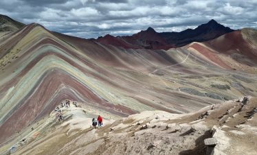 Traveler reaching the summit of Rainbow Mountain Vinicunca on the Ausangate and Red Valley 2 Day Trek from Cusco