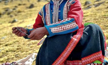 Andean woman in traditional clothing displaying handmade textiles on the Ausangate 7 Lagoons route
