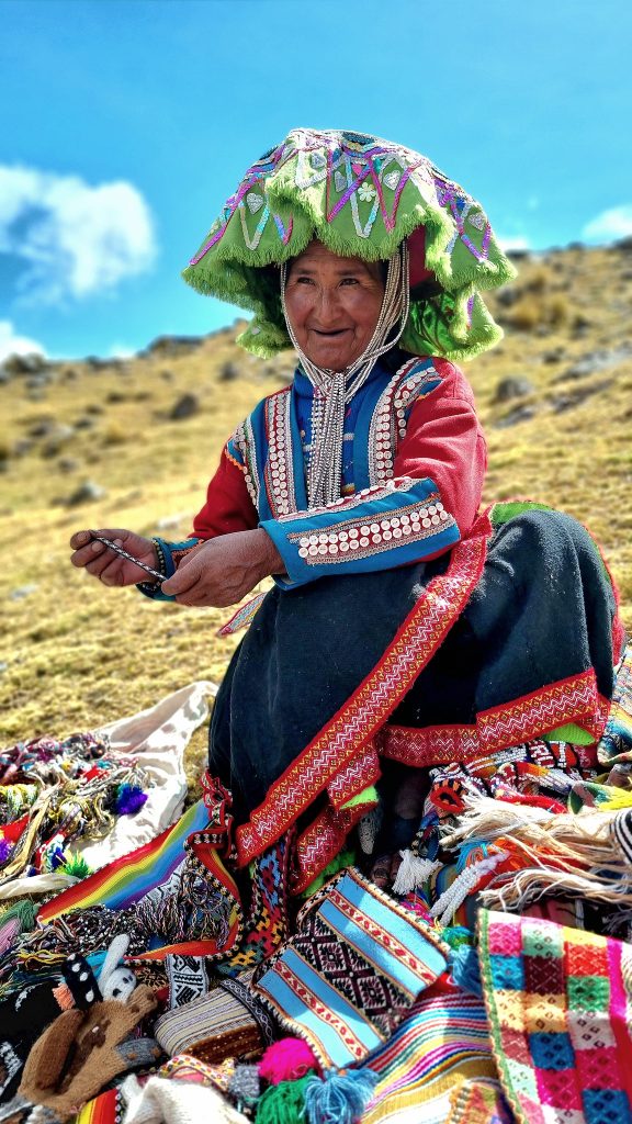 Andean woman in traditional clothing displaying handmade textiles on the Ausangate 7 Lagoons route