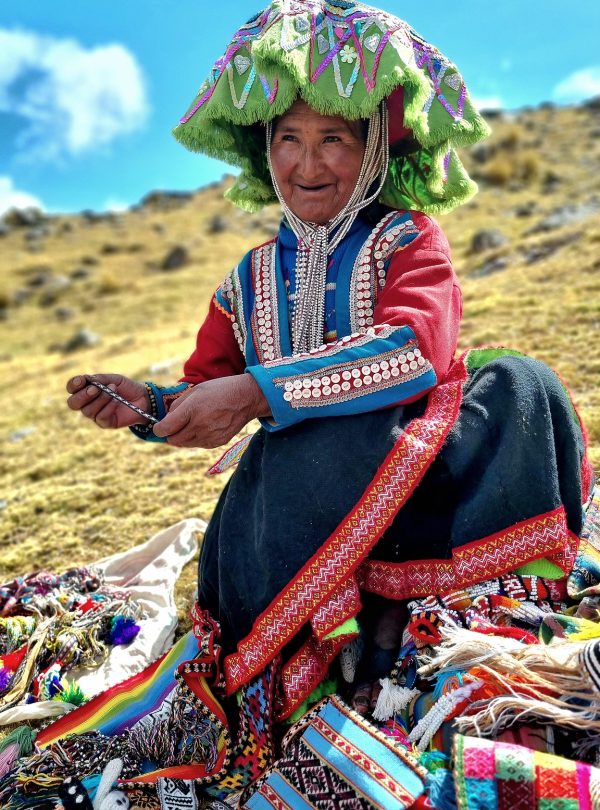 Andean woman in traditional clothing displaying handmade textiles on the Ausangate 7 Lagoons route