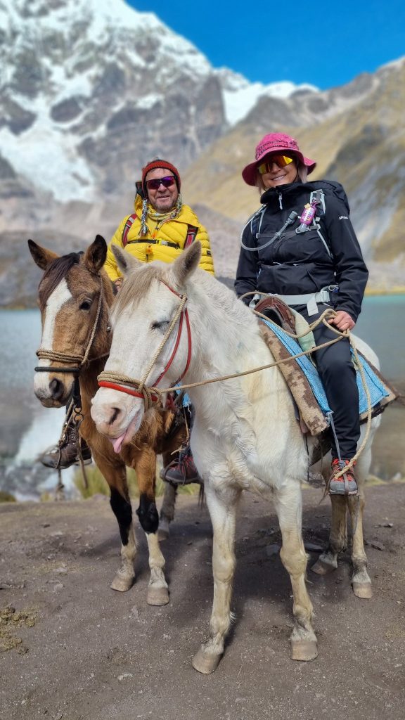 Couple on horseback in front of a lagoon and the Ausangate glacier during the 7 Lagoons tour